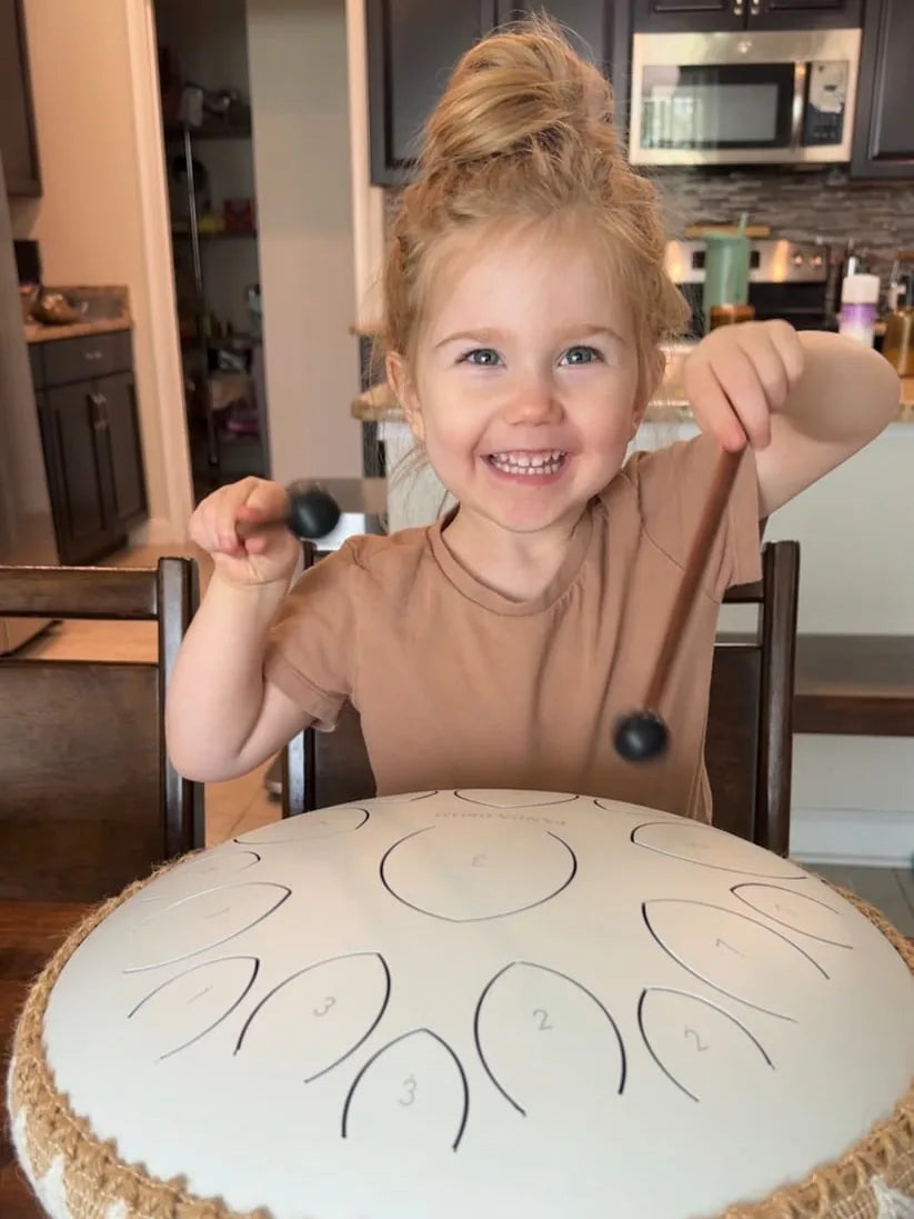 A young child playing a Panda Drum at the kitchen table
