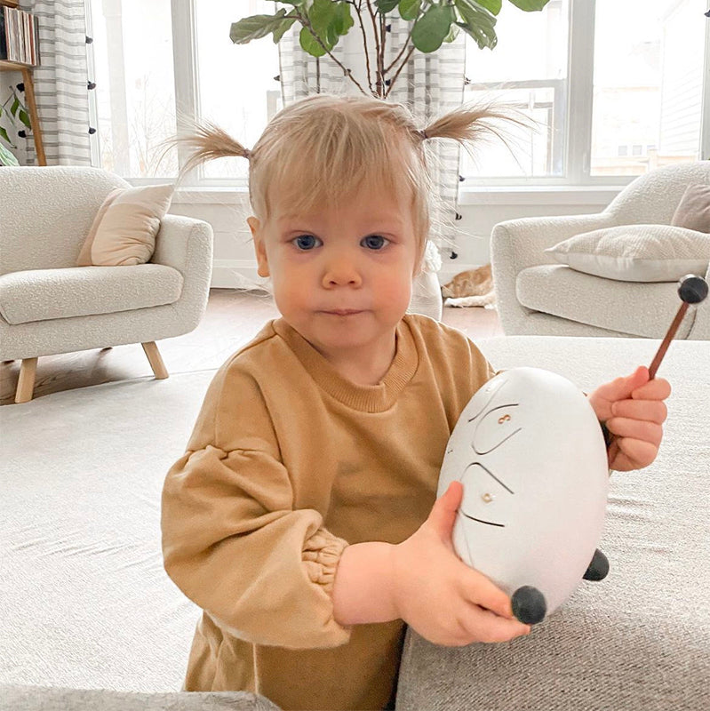 White Girl Toddler Holding  a 8 Tone 6-inch Steel Tongue Hank Tank Panda Drum White with drumstick