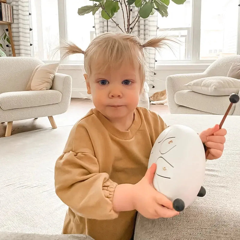 Toddler playing a white Panda Drum